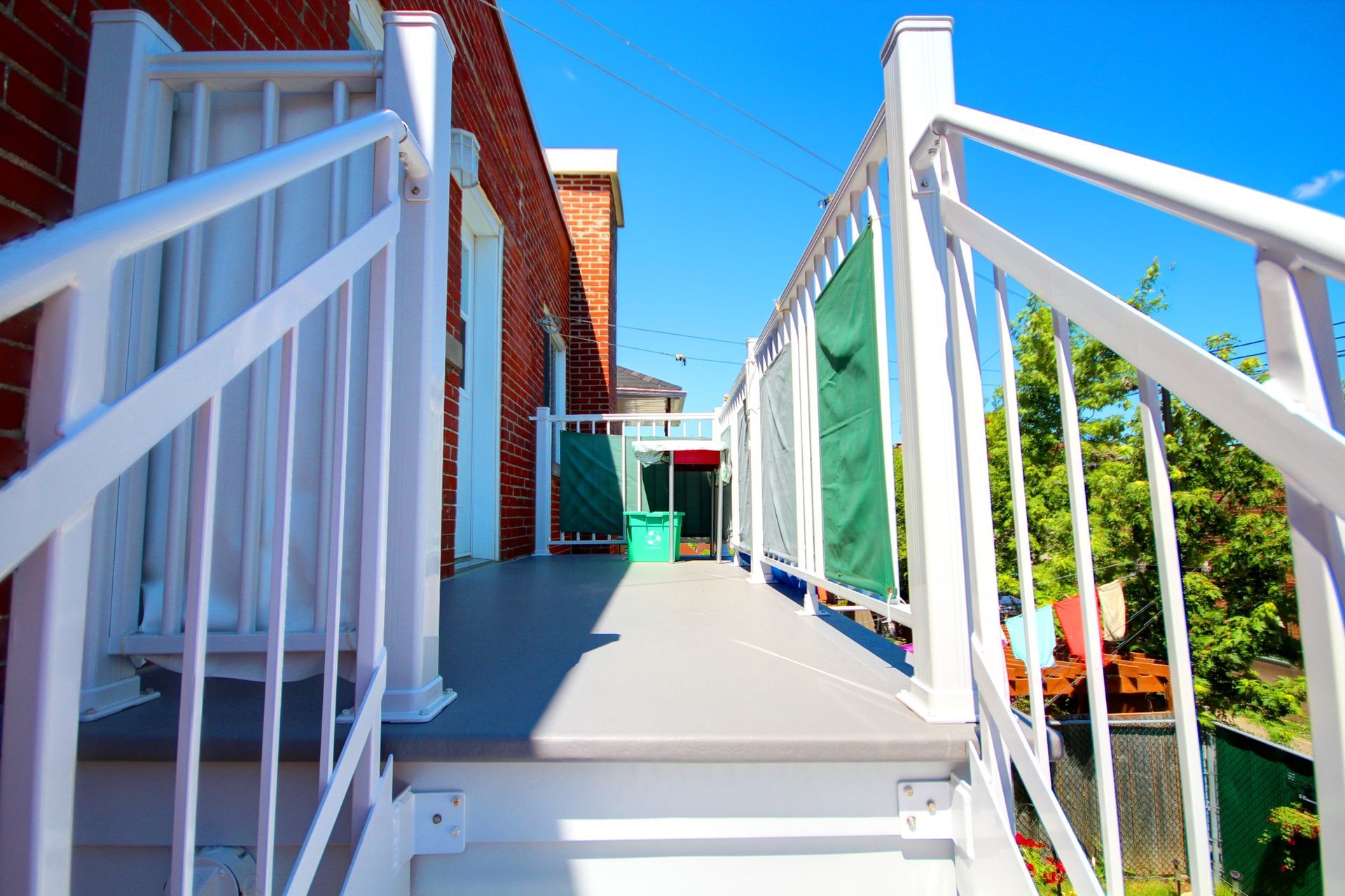 Une balustrade blanche menant à un balcon avec un bâtiment en brique en arrière-plan.
