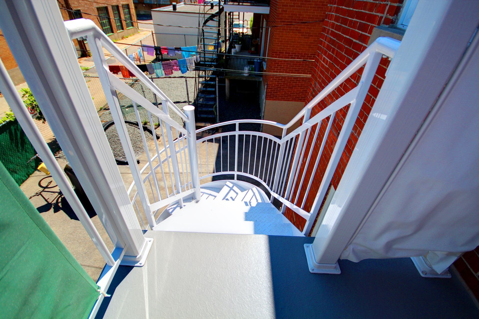 Un escalier en colimaçon avec une balustrade blanche menant à un bâtiment en brique.