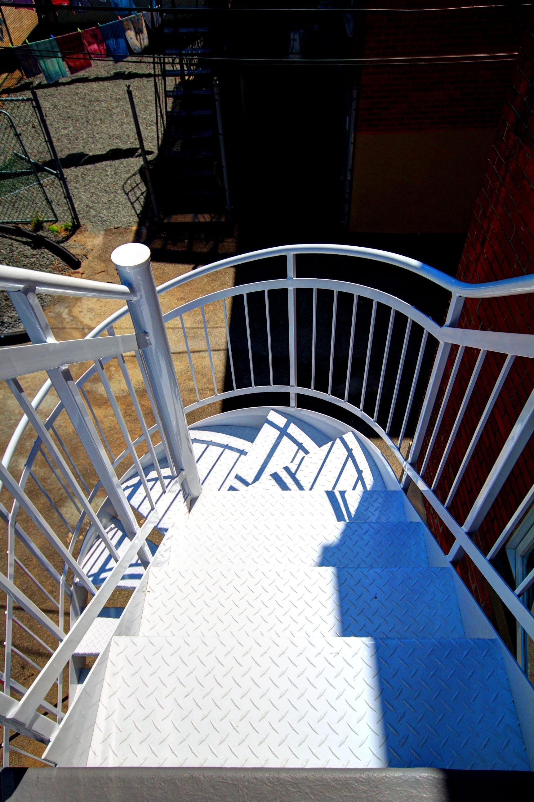 Un escalier en colimaçon avec une balustrade blanche et des marches bleues