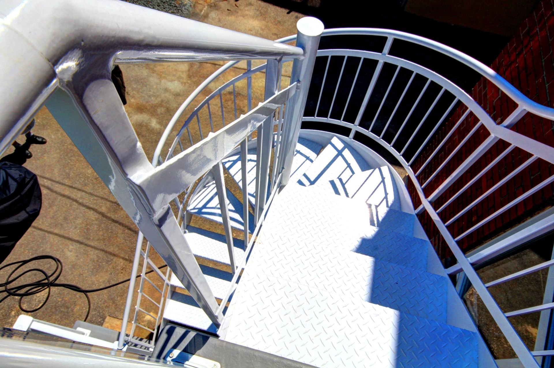 Un escalier en colimaçon avec une balustrade blanche et des marches bleues