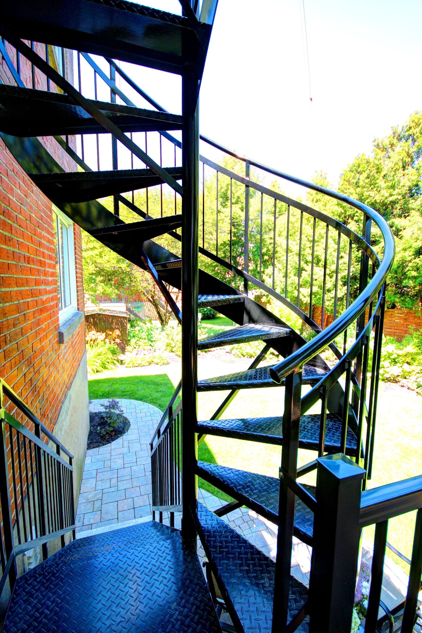 Un escalier en colimaçon mène à un bâtiment en brique.