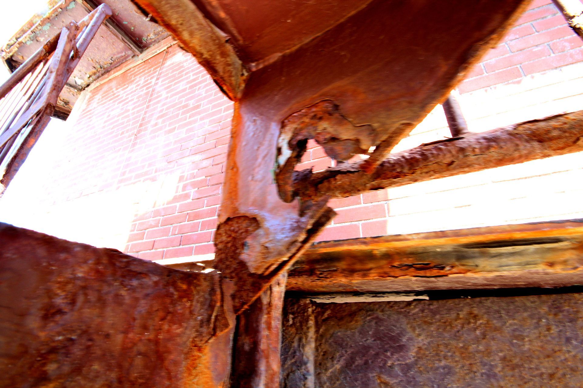 Une structure métallique rouillée avec un mur de briques en arrière-plan