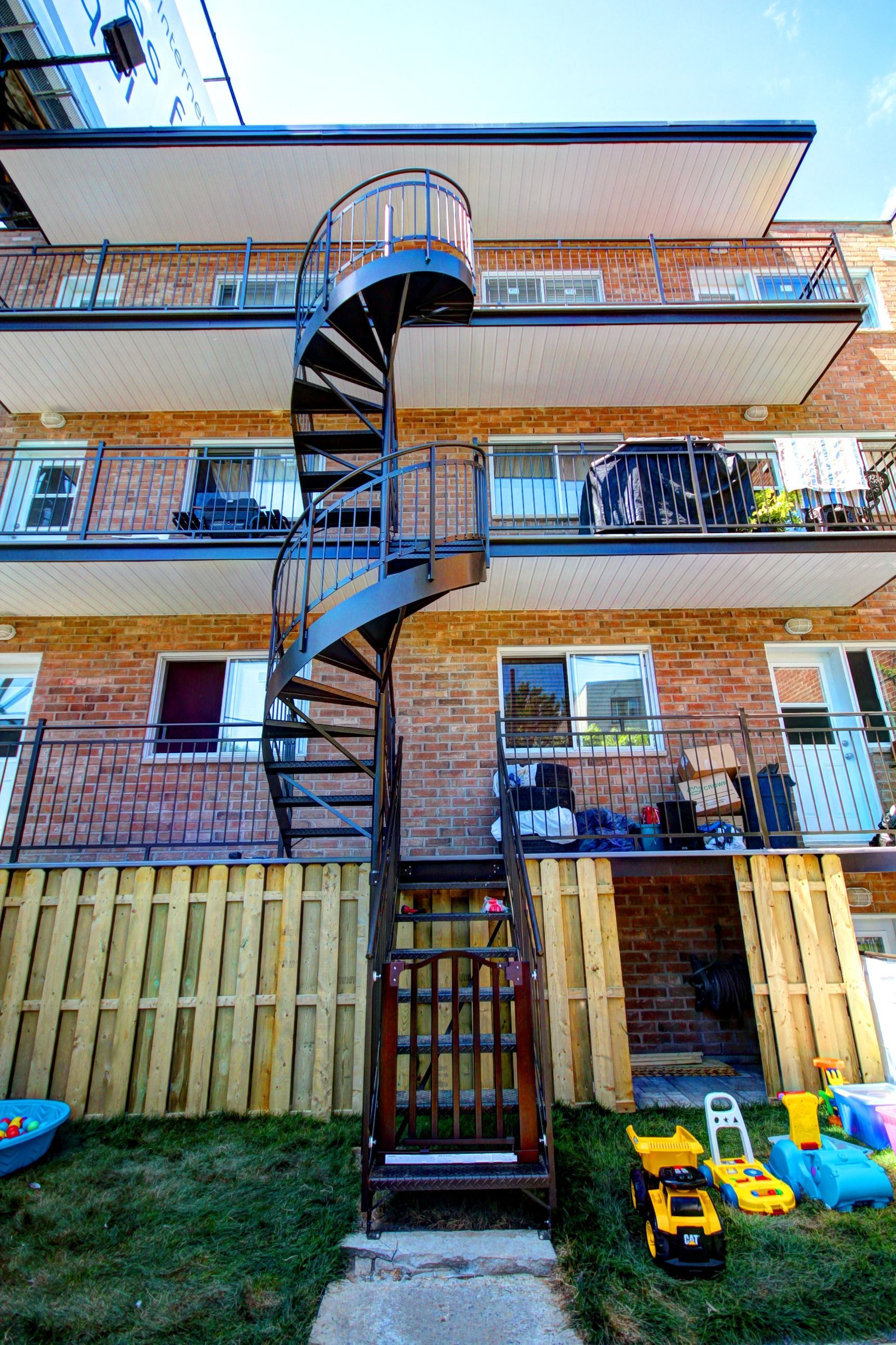 Un escalier en colimaçon mène au deuxième étage d'un immeuble en brique.