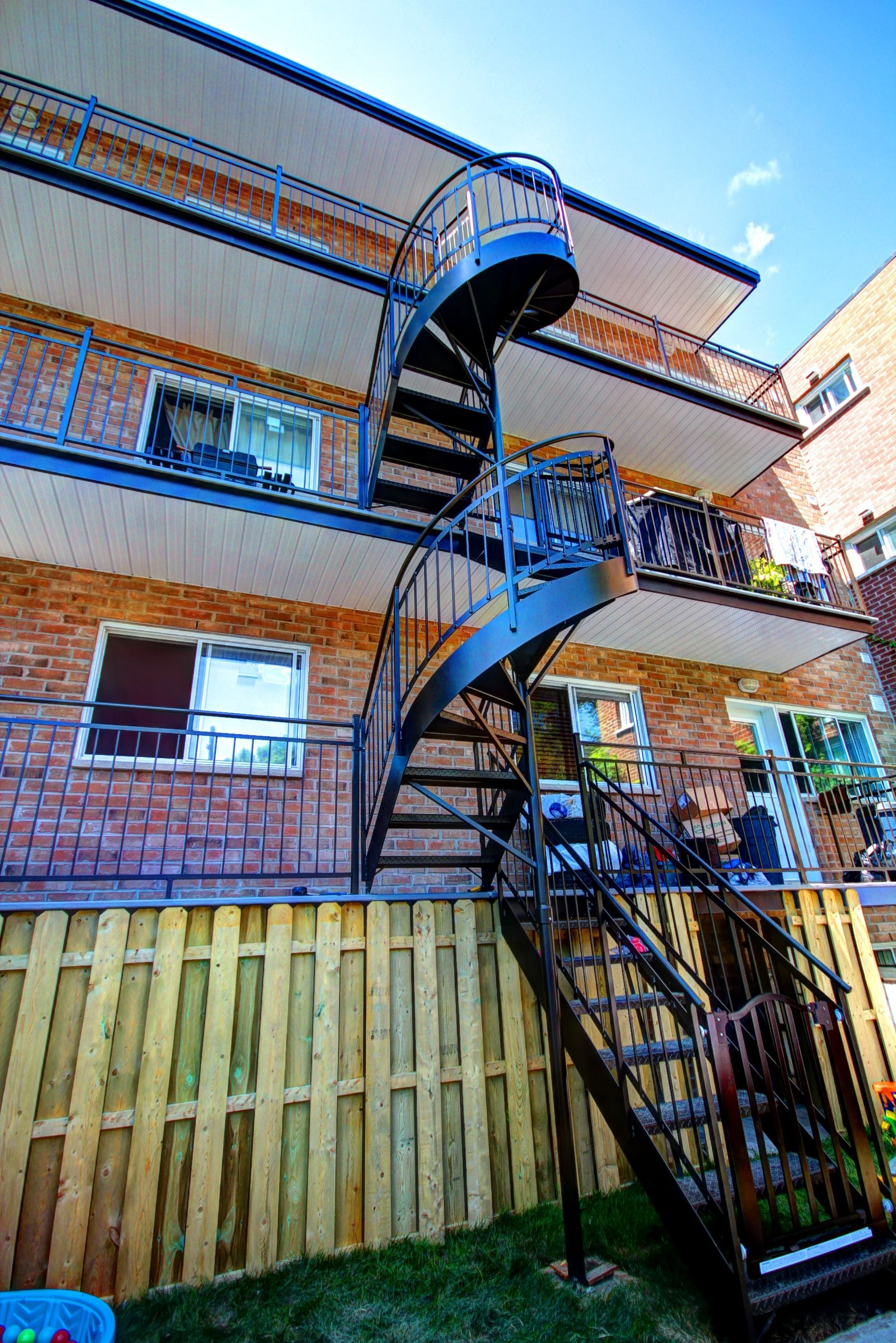 Un escalier en colimaçon mène au deuxième étage d'un immeuble en brique.