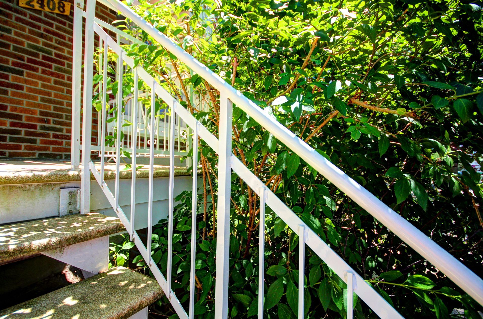 Un escalier avec une balustrade blanche menant à un bâtiment en brique.