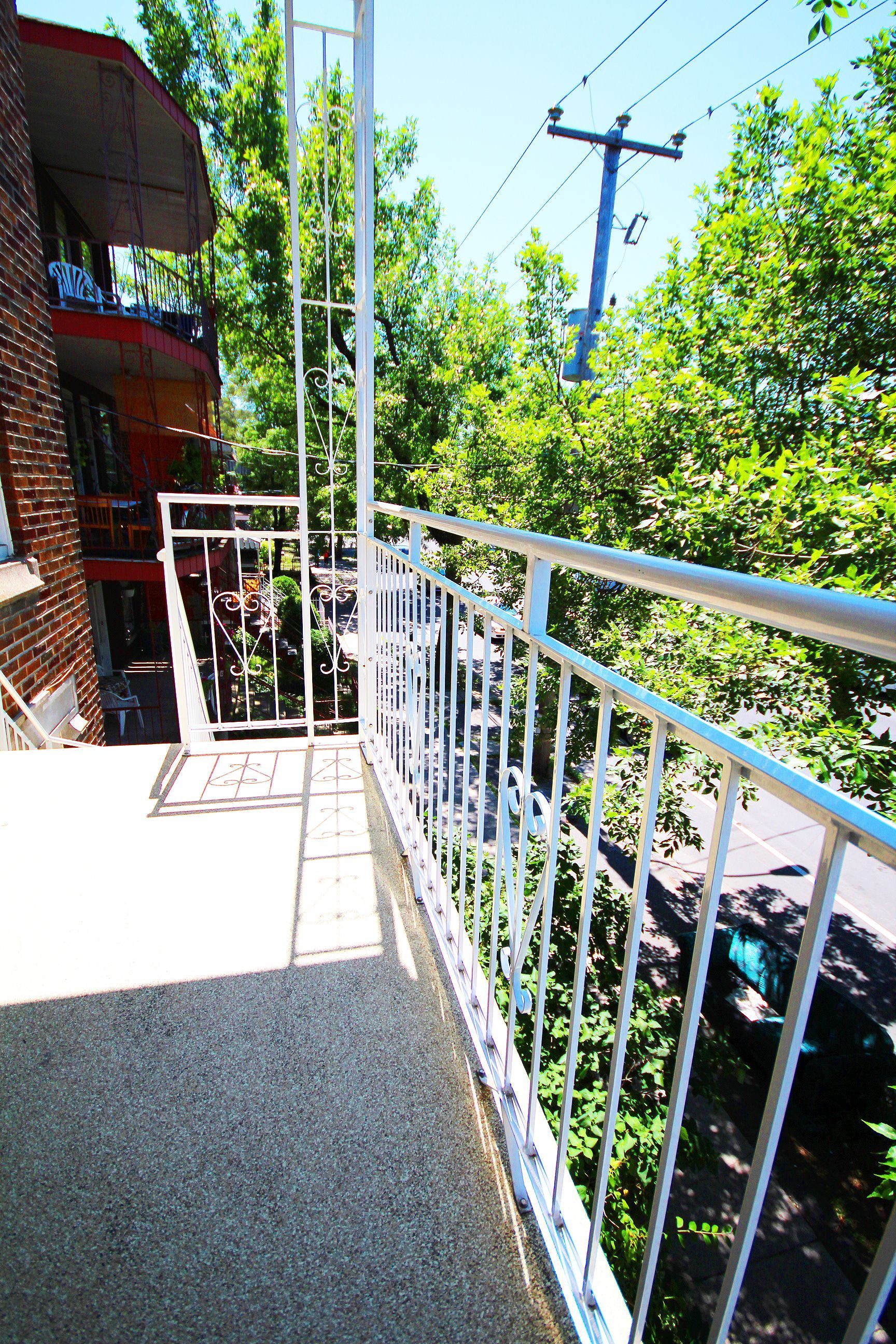 Un balcon avec une balustrade métallique entouré d'arbres