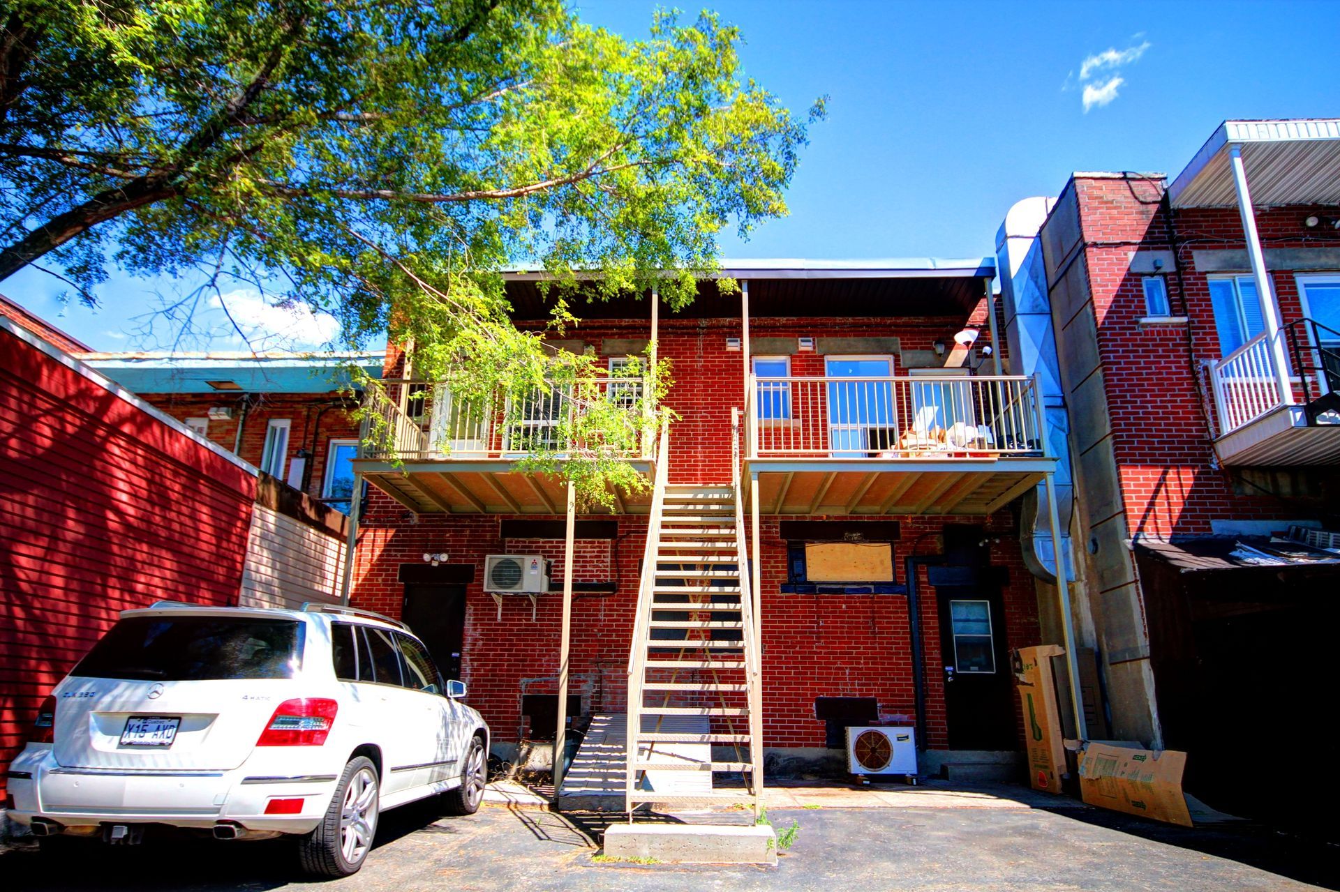 Une voiture blanche est garée devant un bâtiment en brique