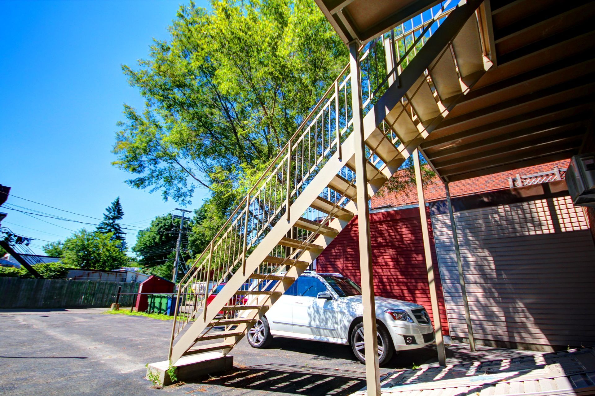 Une voiture blanche est garée sous les escaliers dans un parking