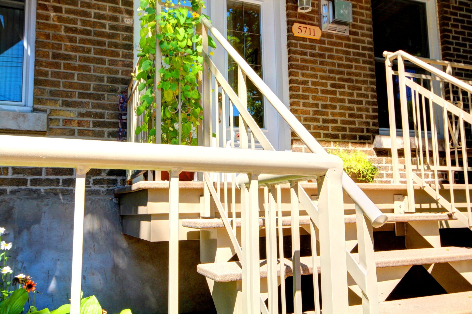 Escaliers menant à une maison en brique avec une balustrade blanche