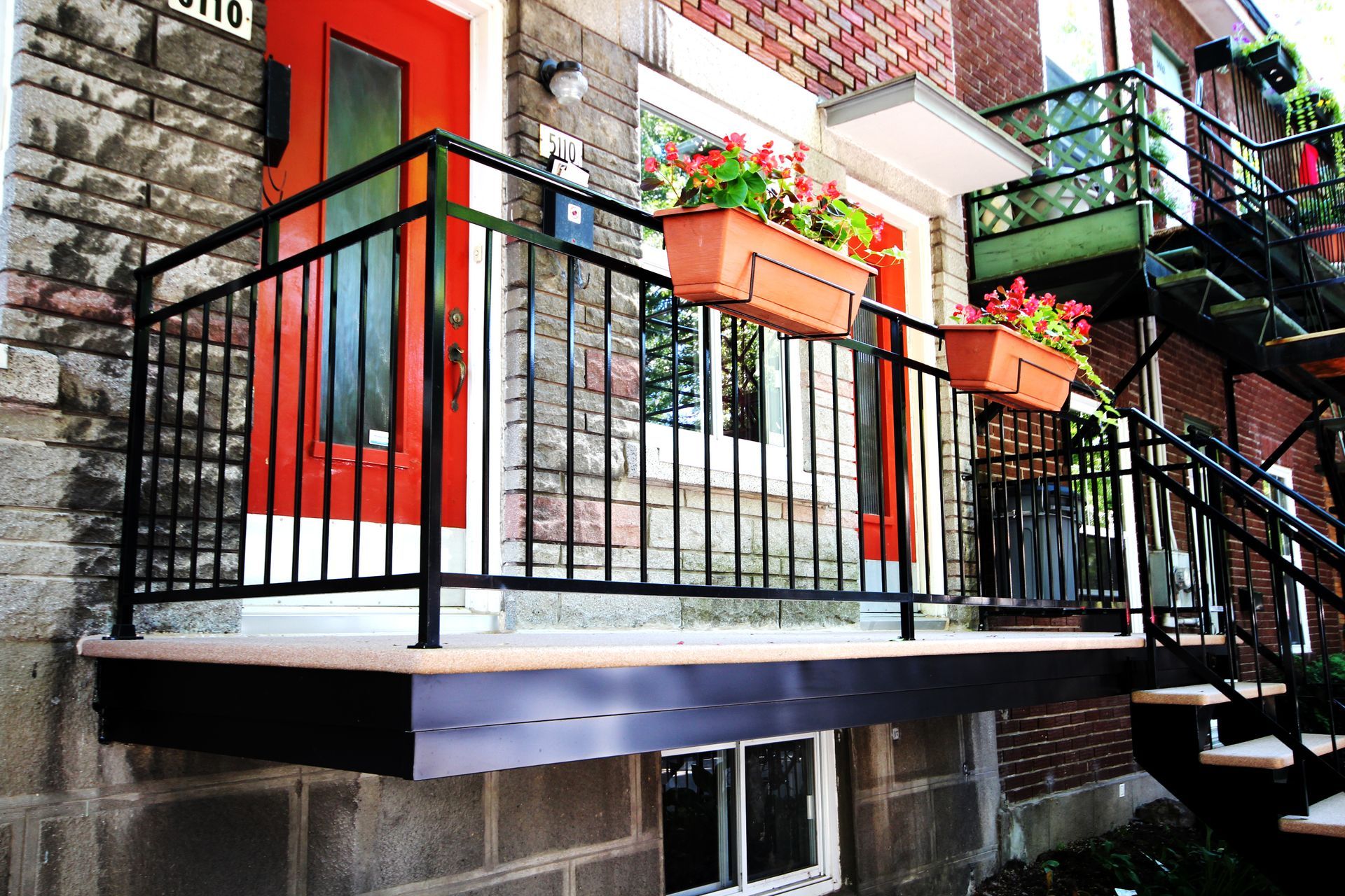 Un balcon avec des escaliers menant à la porte d'entrée d'un immeuble en brique