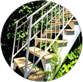 Une photo d'un escalier avec une rampe métallique entourée d'arbres.
