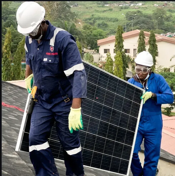 Workers installing solar panels on a rooftop, wearing safety helmets and uniforms.