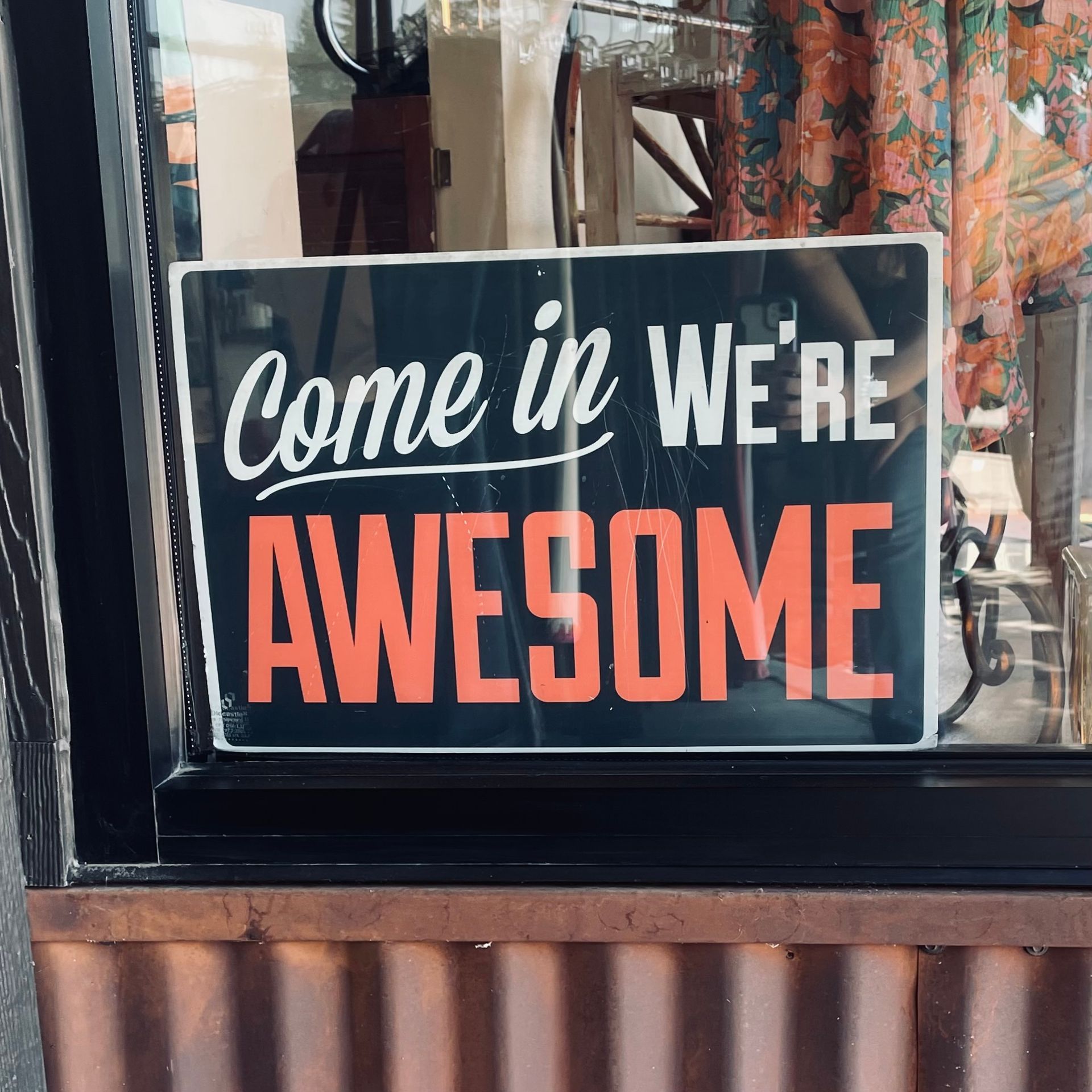 Black sign in a storefront window with white text that reads 