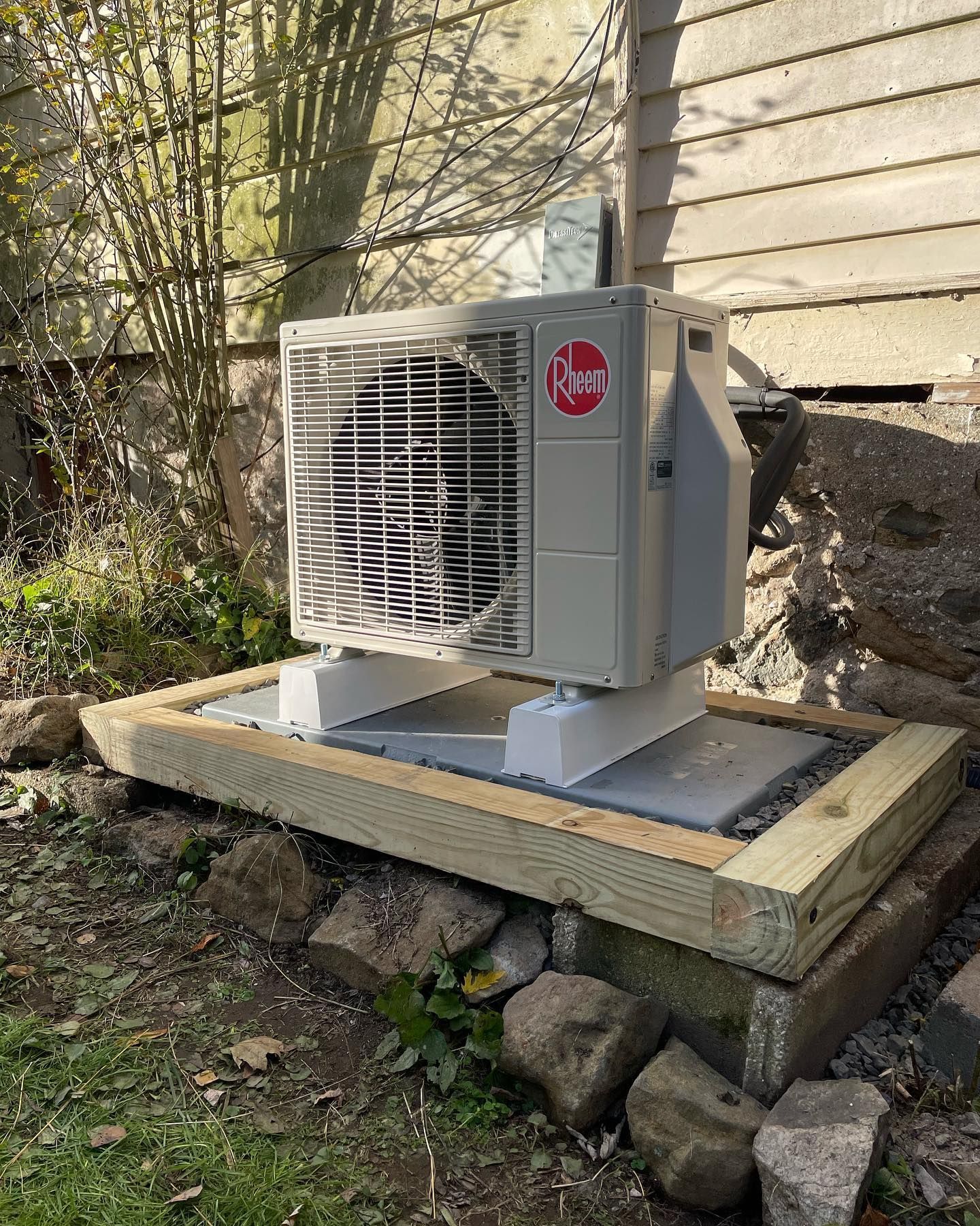 a rheem air conditioner is sitting on a wooden platform