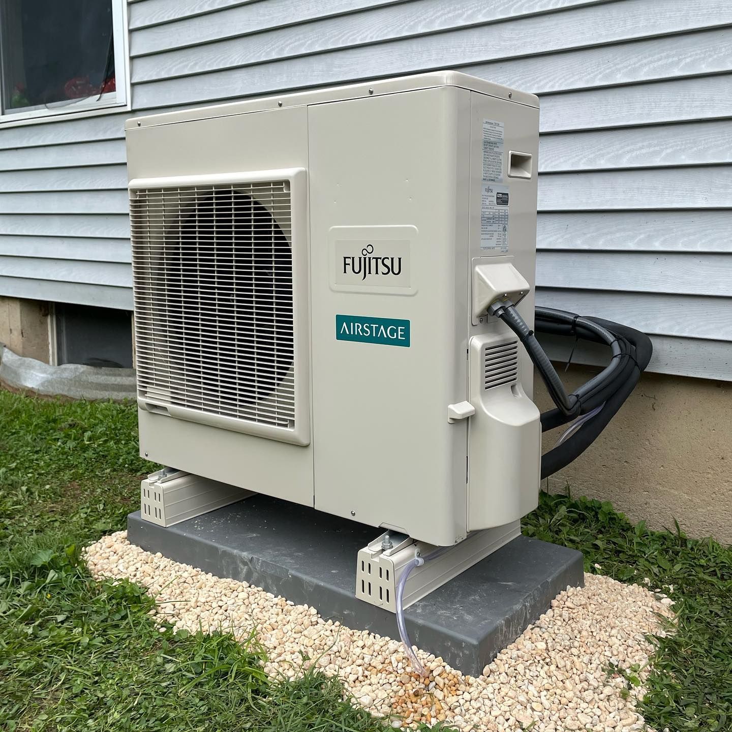 a fujitsu airstage air conditioner sits outside of a house