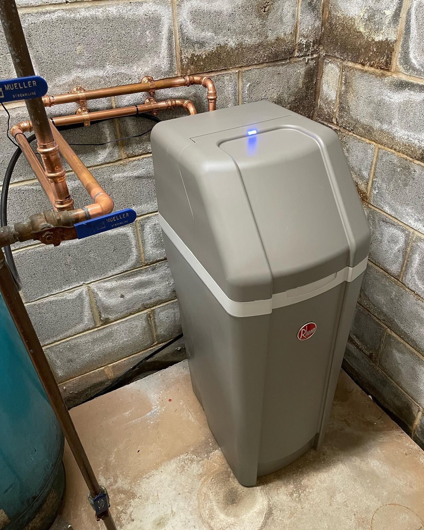 a gray water softener with a blue light on the top