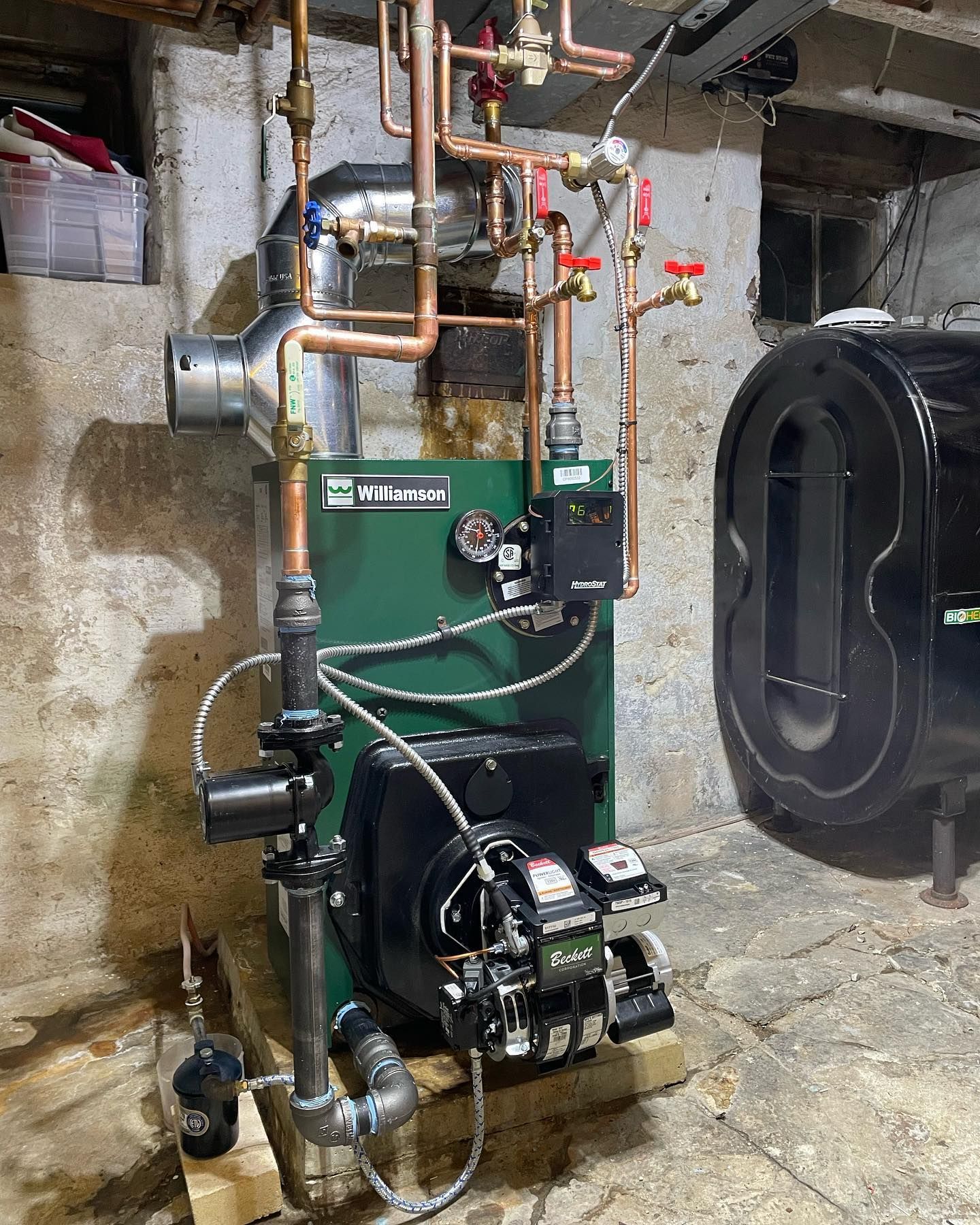 a green williamson boiler sits in a basement