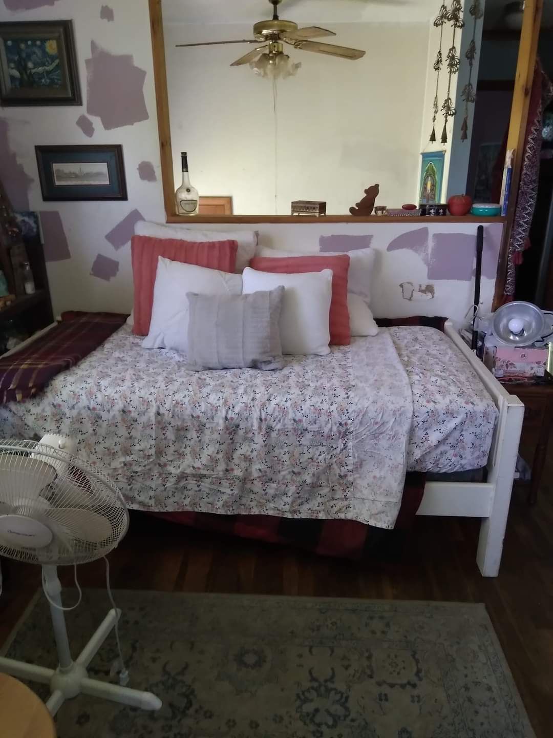 A bedroom with a bed a fan and a mirror