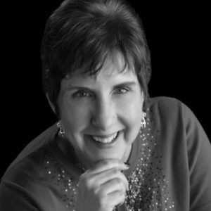 headshot of Kate Applebee with patterned shirt and grey background