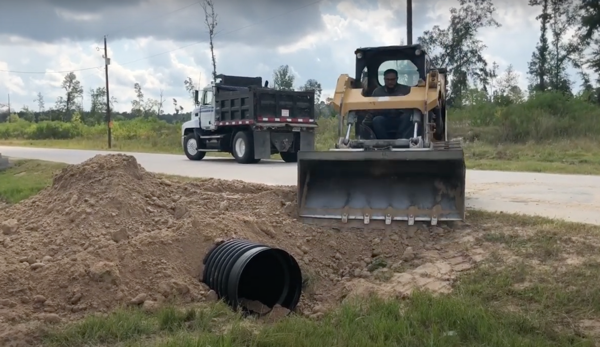 Backfilling dirt around a culvert and drainage ditch.