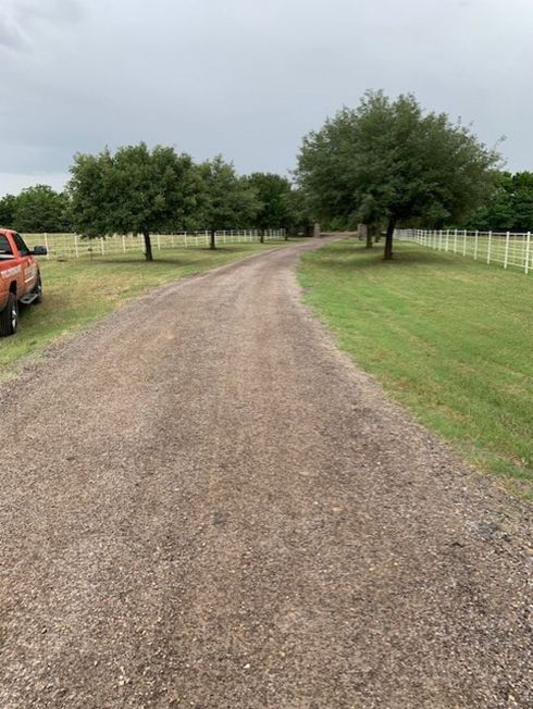 A red truck sitting next to a new gravel driveway on a ranch.