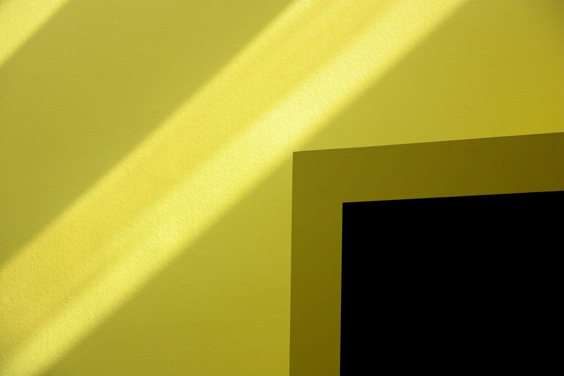 El sol brilla per una finestra en una paret groga.