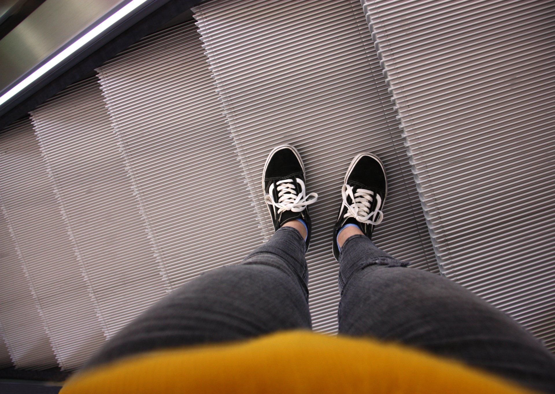 Una persona que porta sabatilles blanques i negres està parada en unes escales.