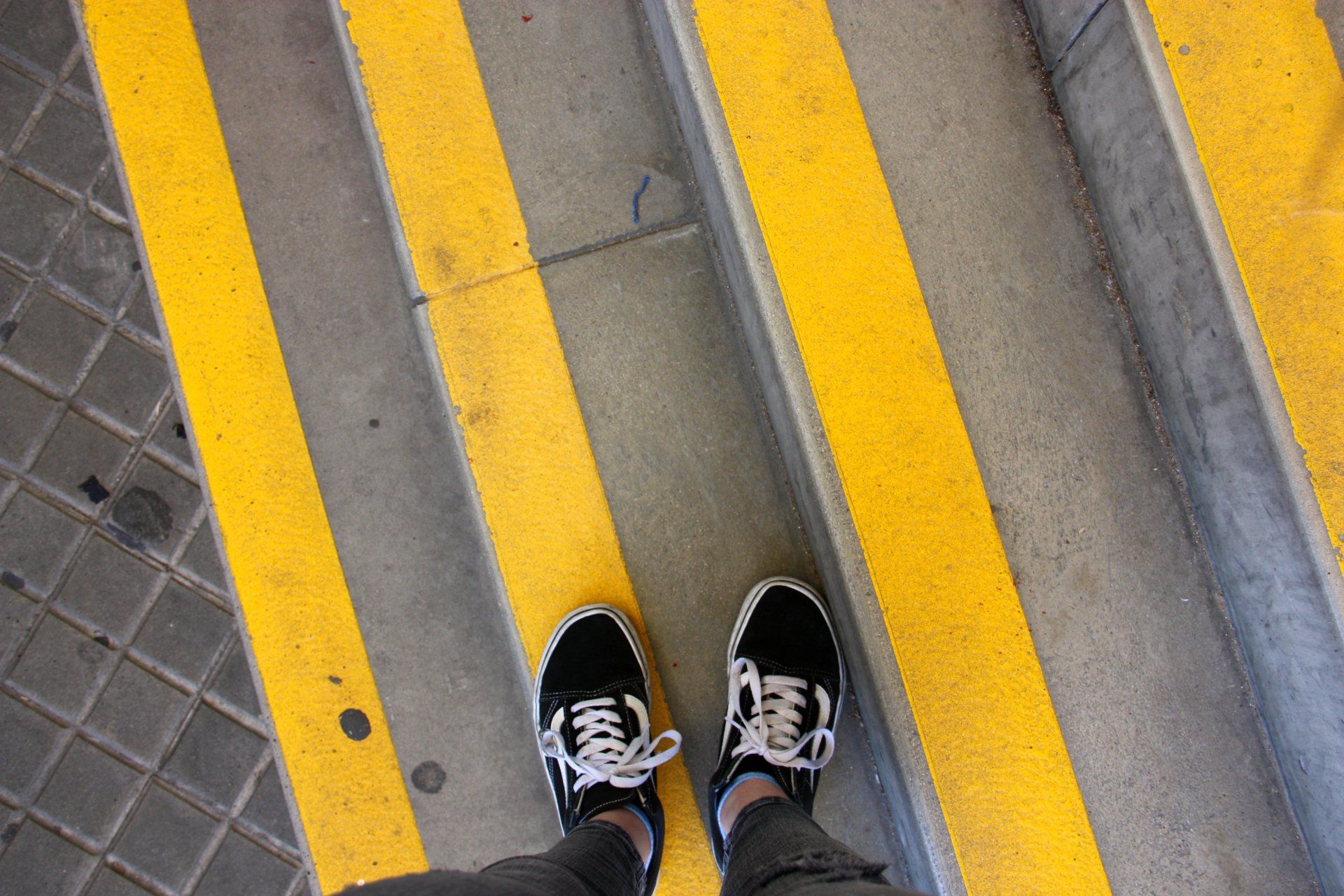 Una persona està parada en un conjunt d'escales amb ratlles grogues.