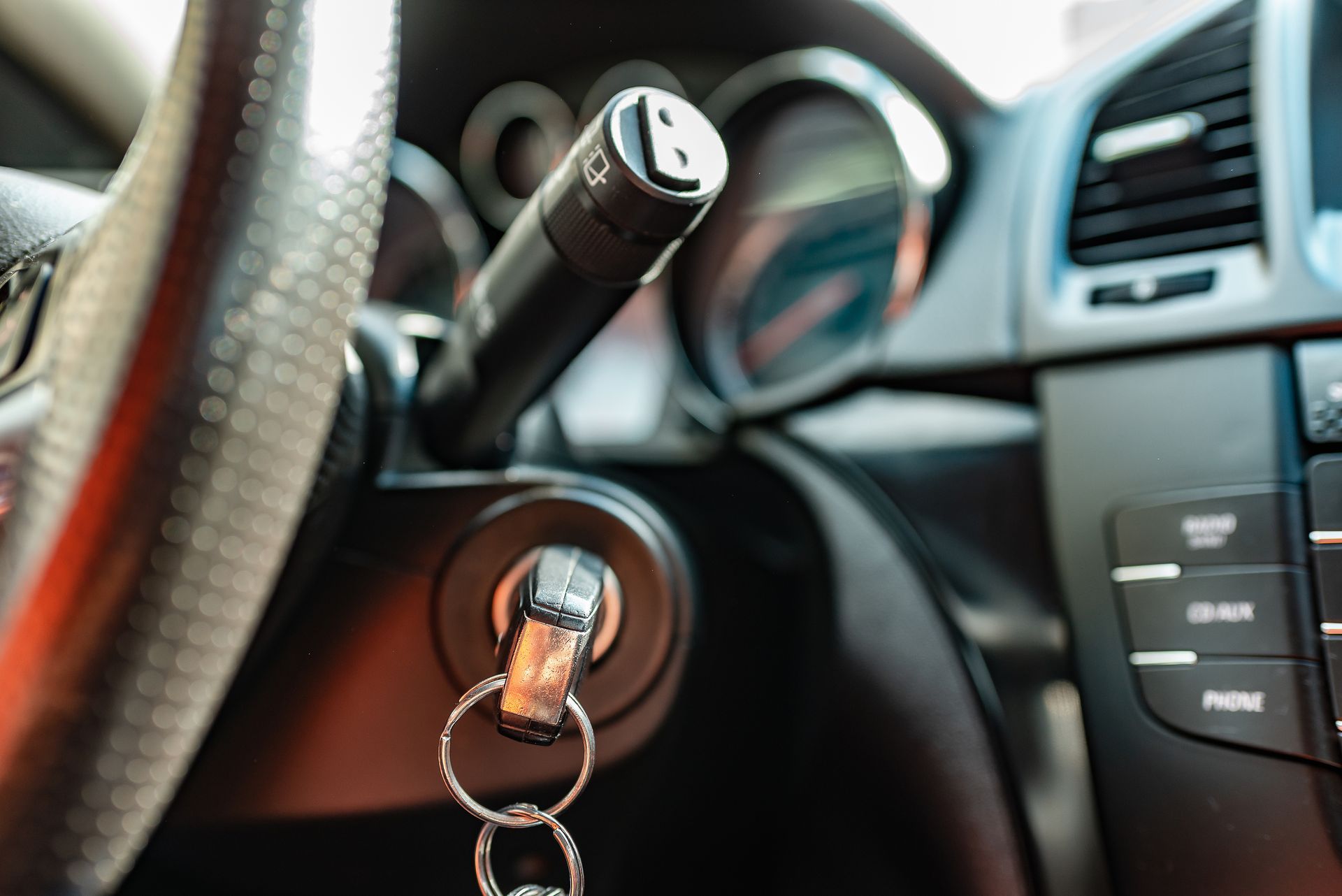 A close up of a car steering wheel with a key in it.