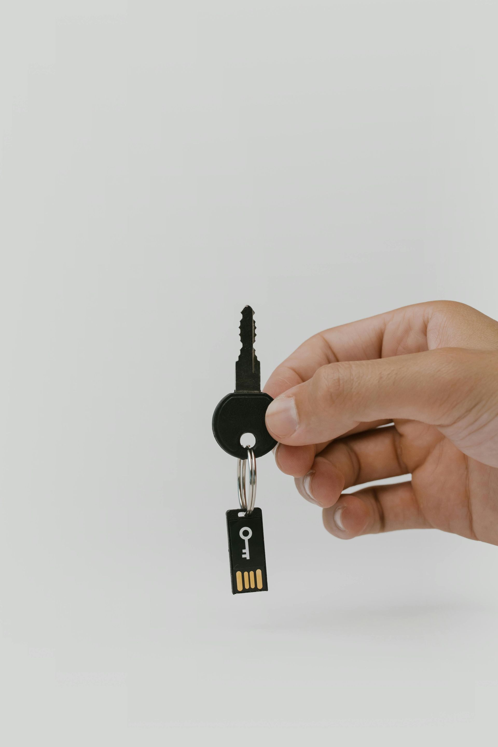 A person is holding a key with a usb stick attached to it.