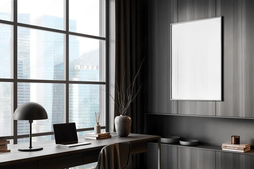 A home office with a desk , chair , lamp and a large window.