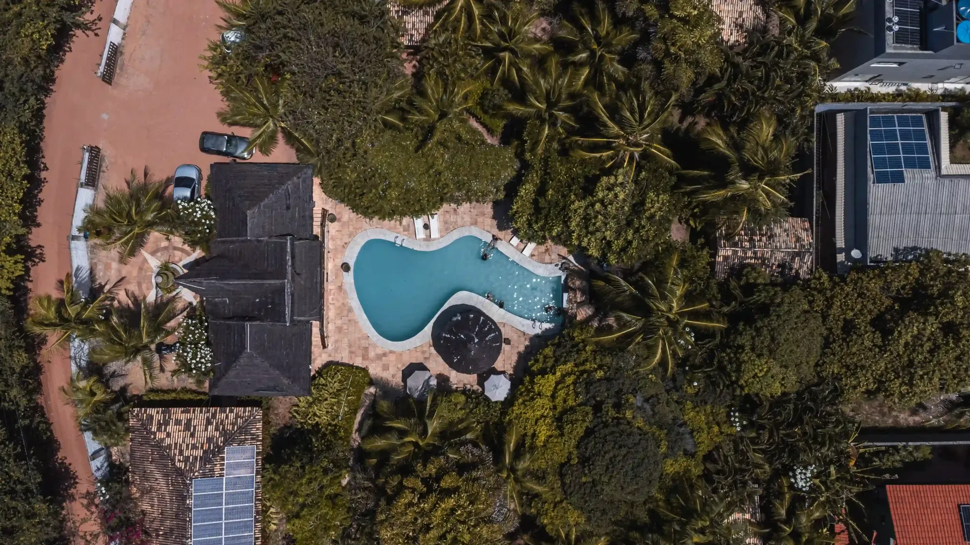 Uma vista aérea de uma piscina cercada por árvores e casas-Pousada-Imperio-do-Sol