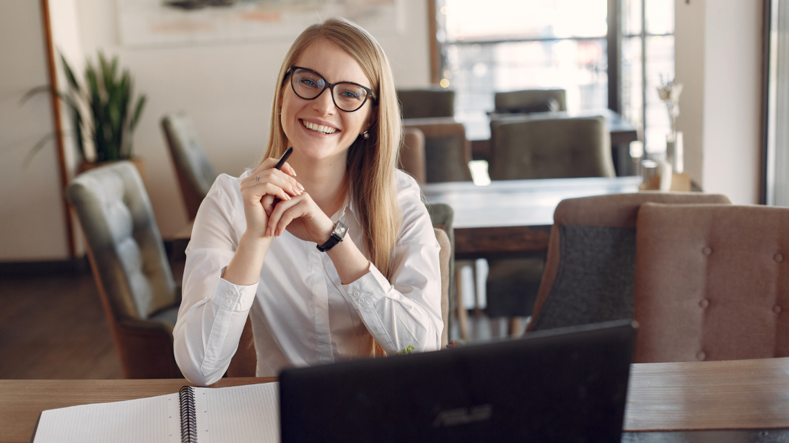 A woman is sitting at a desk in front of a laptop computer.