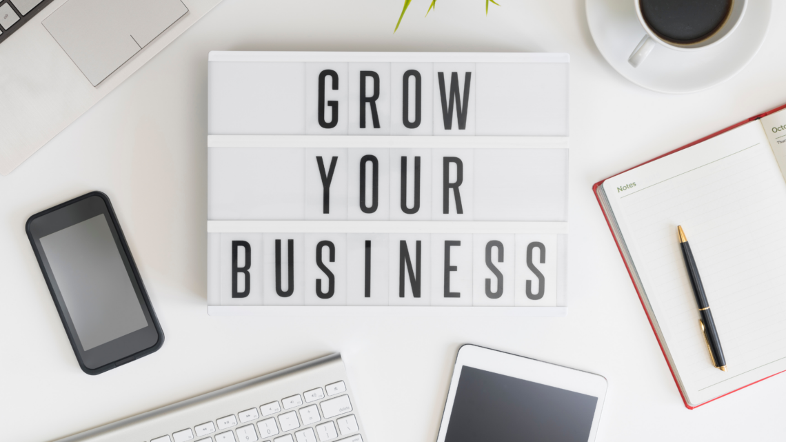 A sign that says `` grow your business '' is sitting on top of a desk.