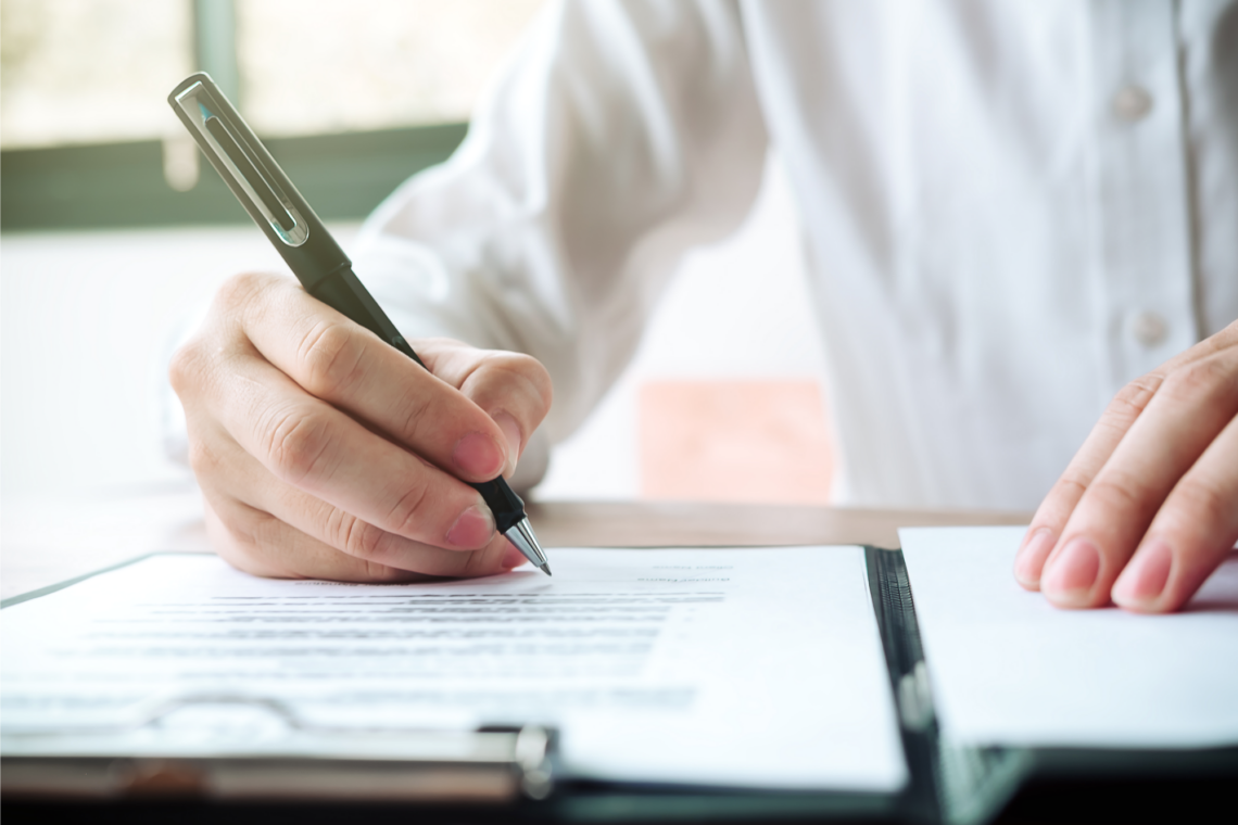 A person is writing on a piece of paper with a pen.