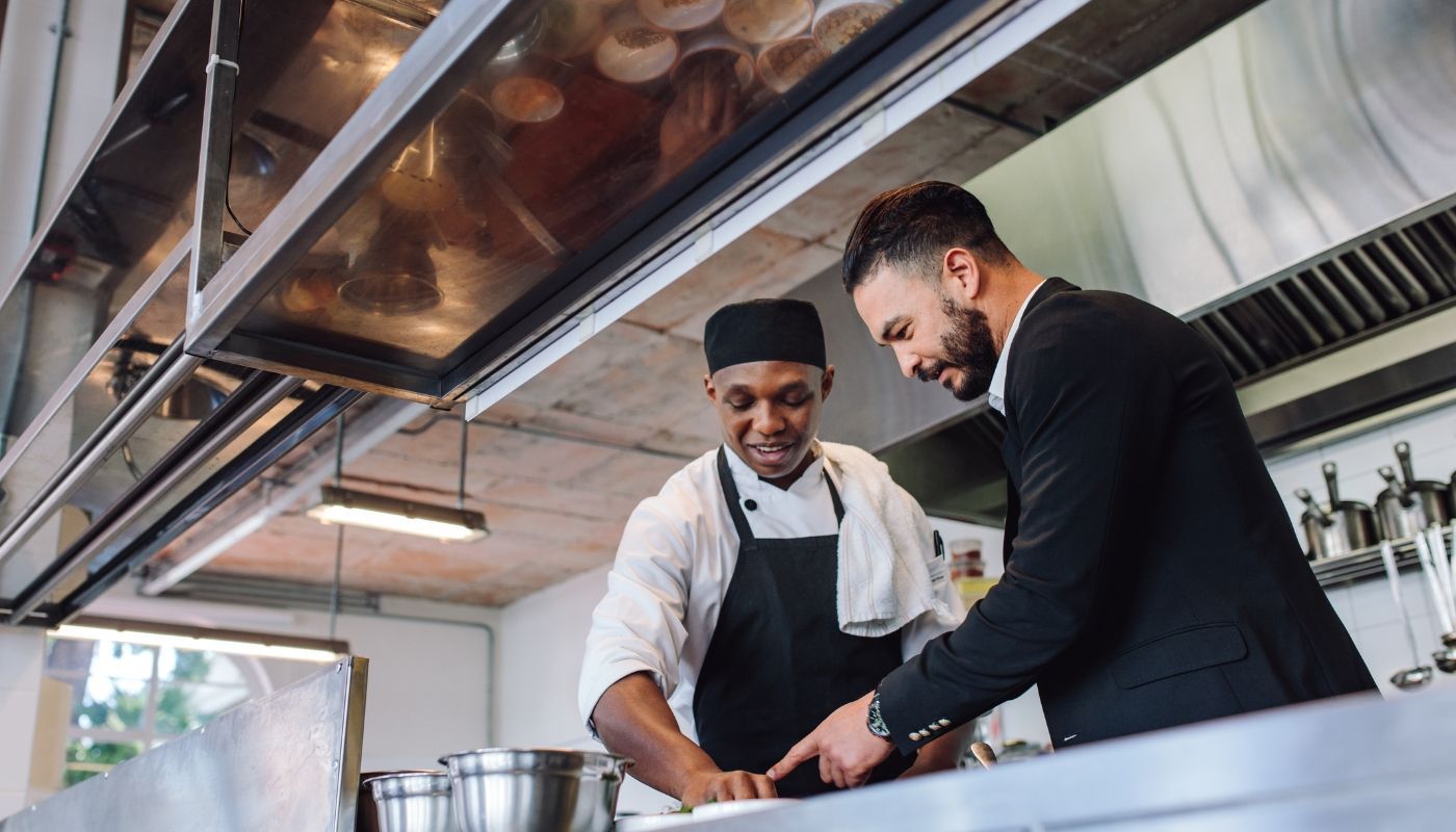 Multi-unit franchise restaurant owner consulting with his chef