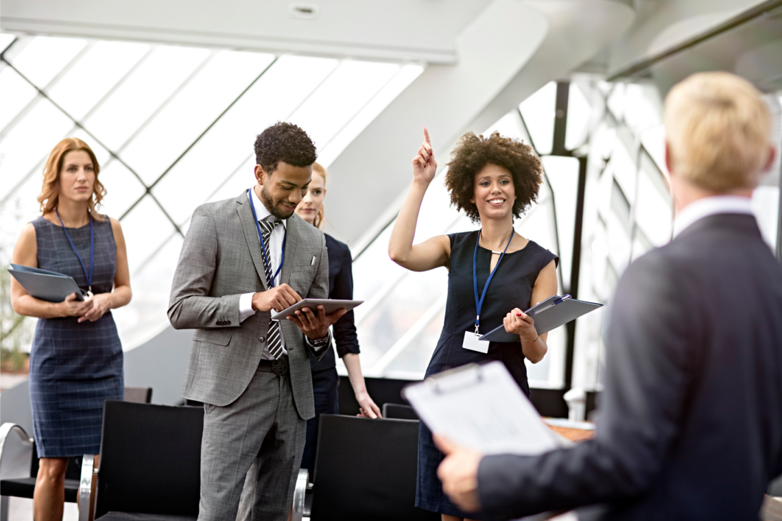 A group of business people are standing around a table in a conference room.