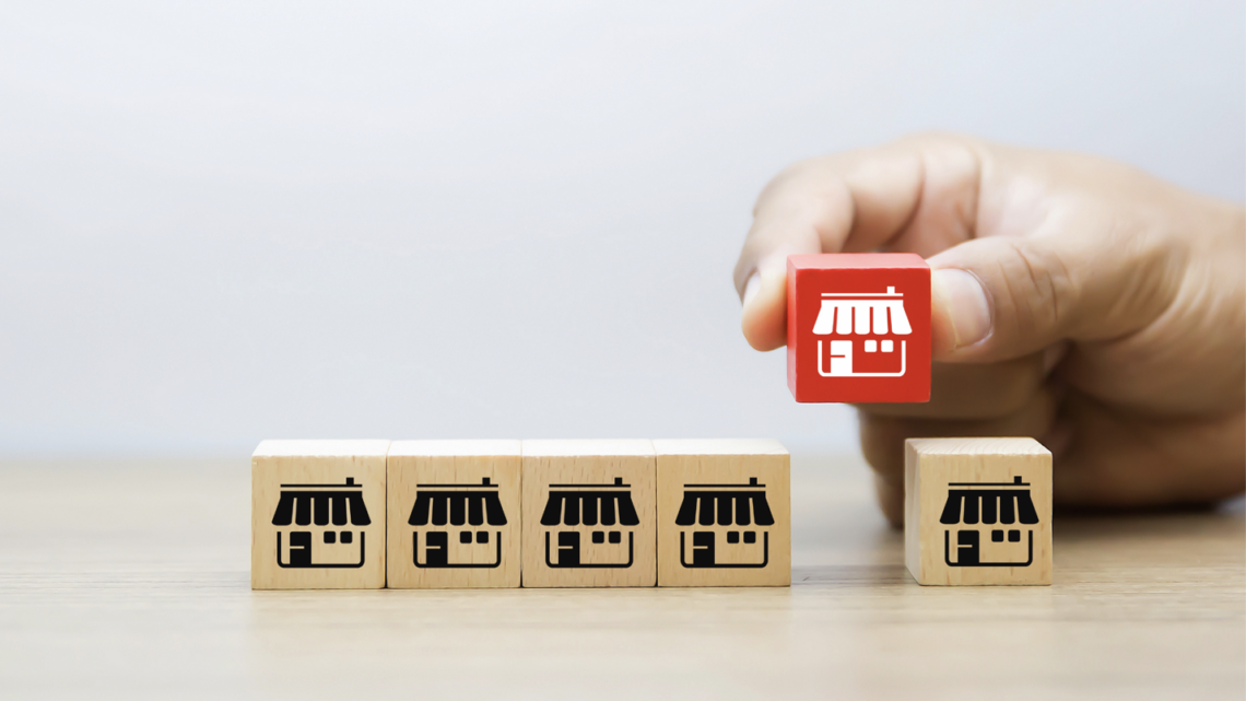 A person is holding a red block with a store front on it.