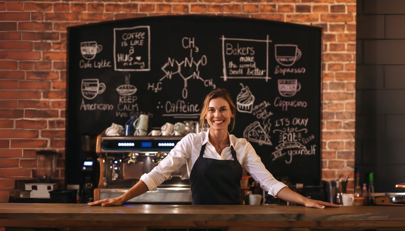 Single-unit franchise cafe owner standing behind bar