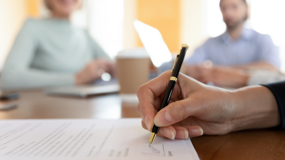 A person is writing on a piece of paper with a pen.