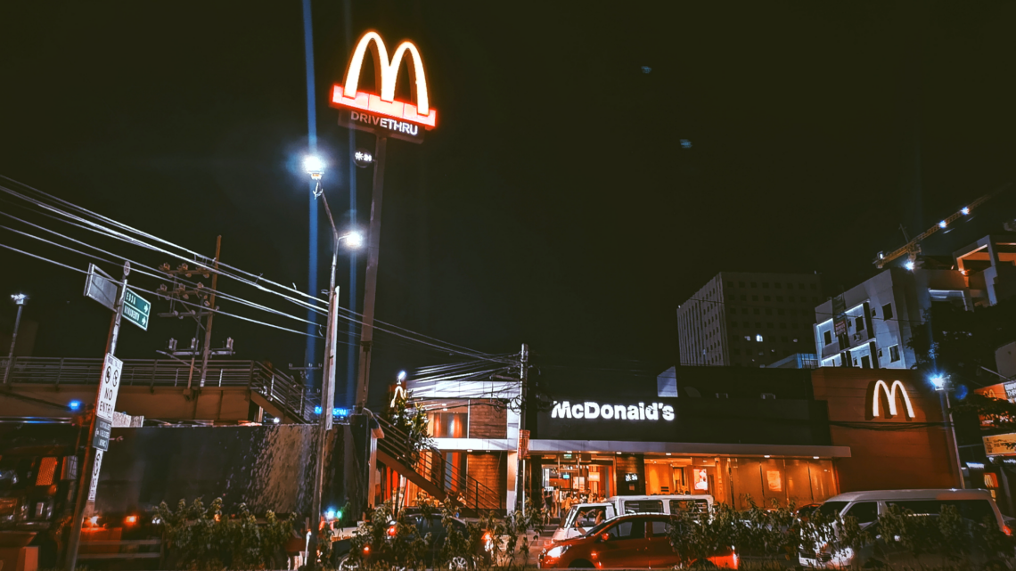 A mcdonald 's restaurant is lit up at night.