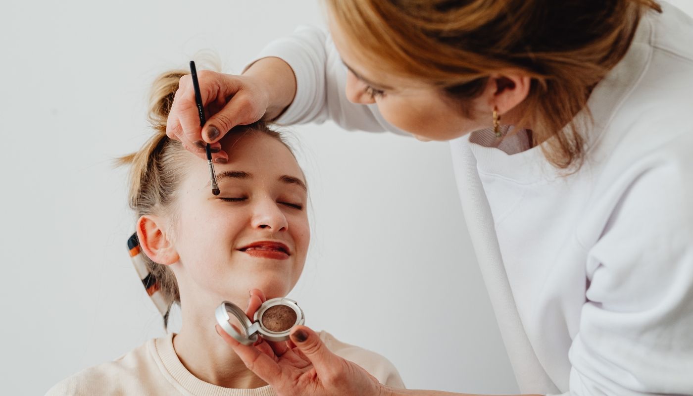 A young woman getting her makeup done by an artist from a beauty franchise app
