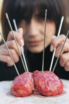 A woman is holding a bunch of needles in front of a brain