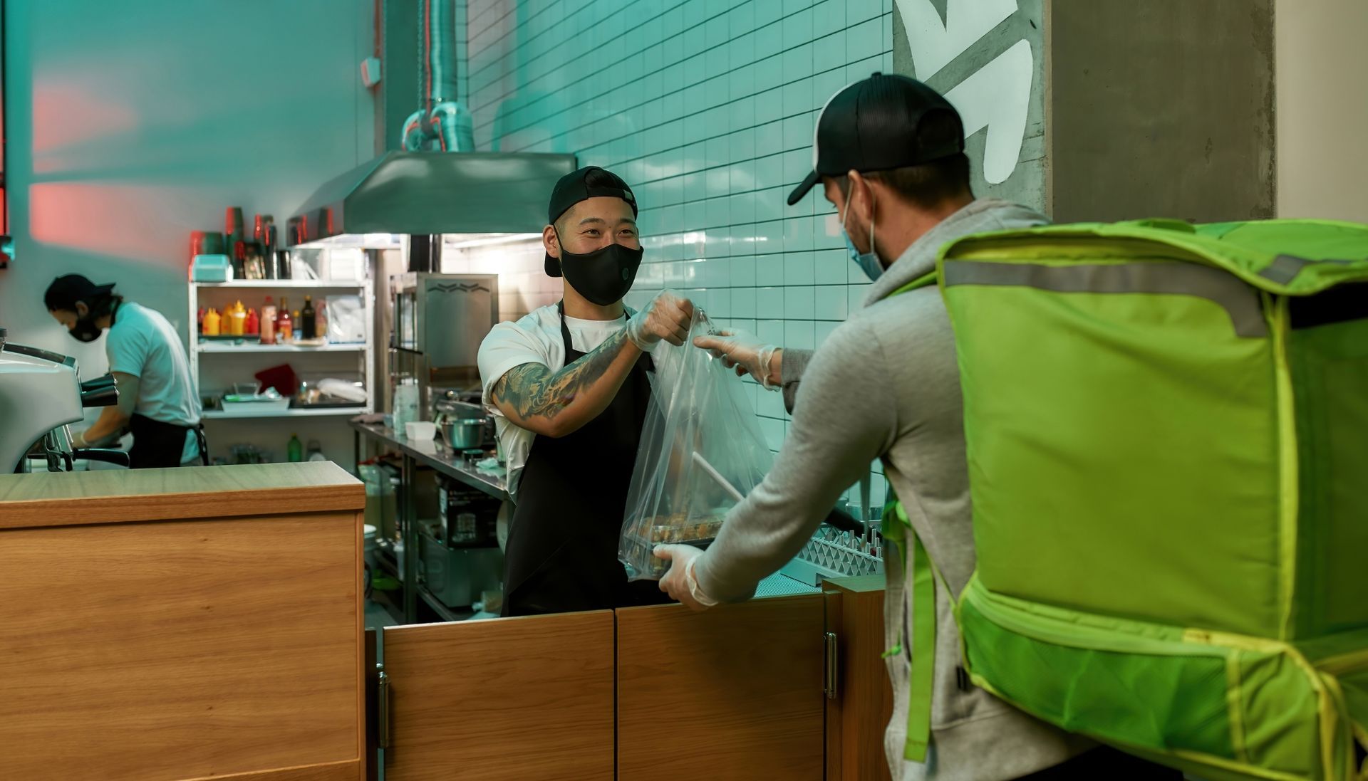 Restaurant staff handing deliverables to a man working for a food delivery franchise