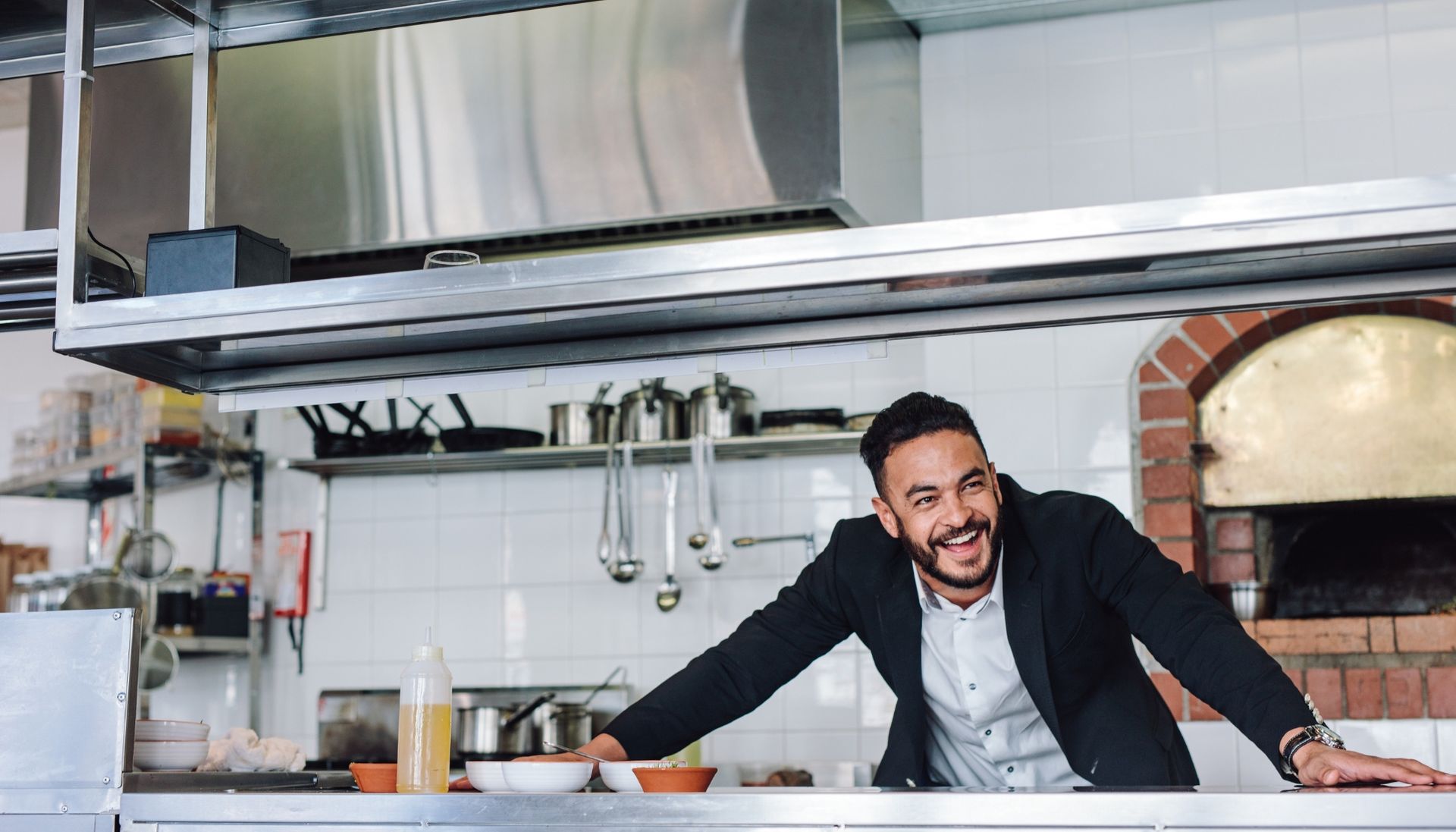 Happy food franchise owner standing behind a kitchen counter
