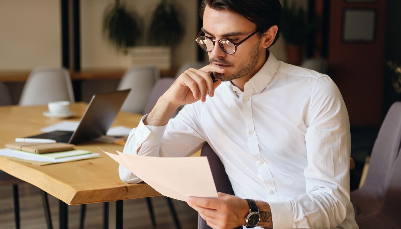 Young businessman thoughtfully reading a contract during the franchise buying process