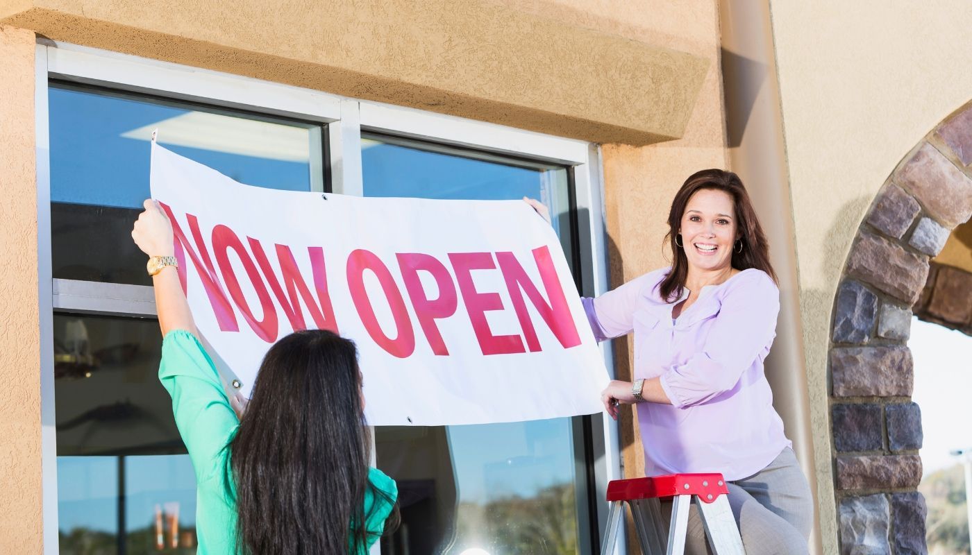 A franchisee at a grand opening, putting up a now open sign.