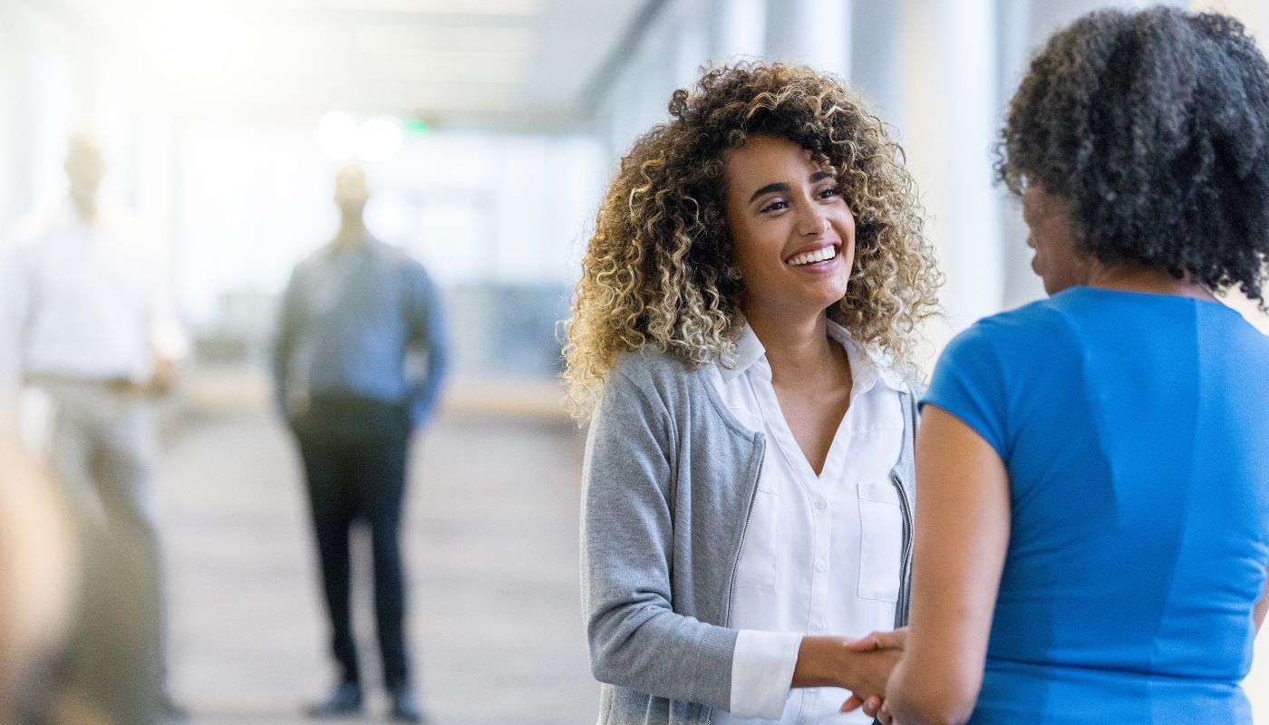Two business women shaking hands and building wealth through franchising.