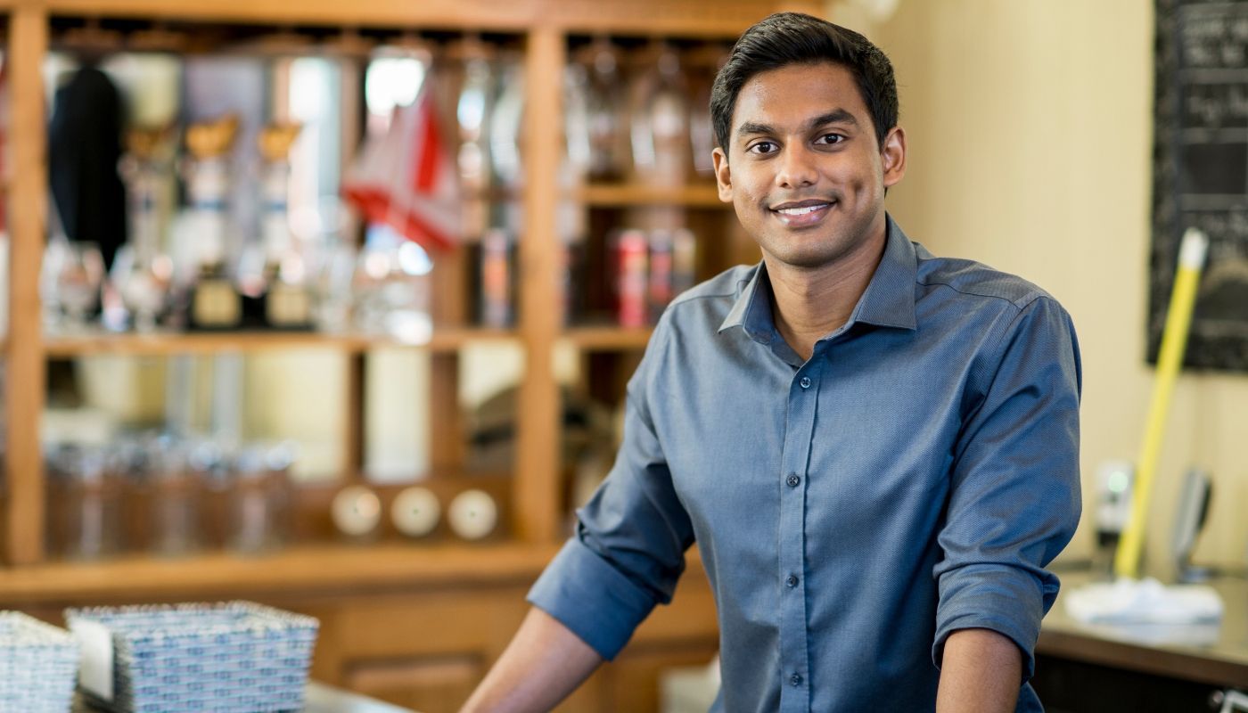 Semi-absentee business owner standing behind a wooden counter.