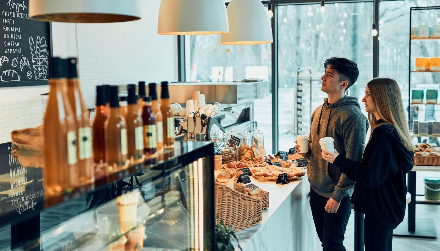Man and woman ordering drinks at a cozy coffee shop, representing one of the best winter-friendly franchises for cold-season demand.